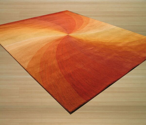 A low pile rug featuring a swirling pattern of orange, red, and yellow rests on light wood plank flooring.