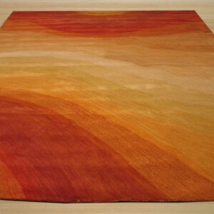 Abstract rug displaying a wavy gradient of red, orange, and gold colors on light wooden flooring.