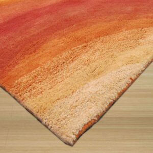 Shaggy rug corner displaying a high-pile red, orange, and cream color gradient on light wood flooring.