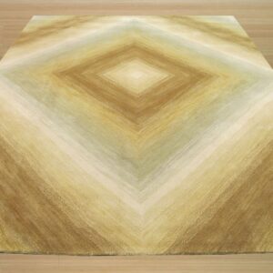 A rug with brown, gold, and tan striations forming a large central diamond pattern on wood floor.