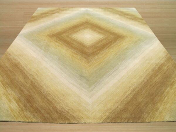 A rug with brown, gold, and tan striations forming a large central diamond pattern on wood floor.