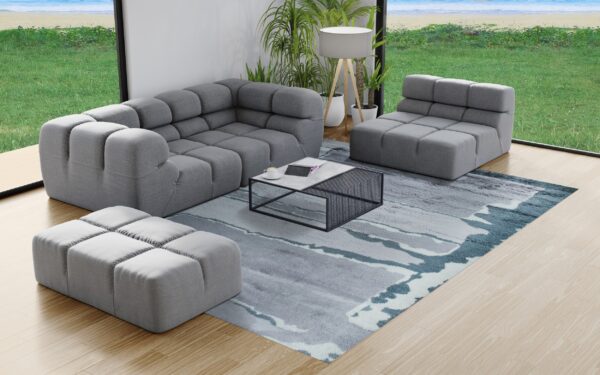 Abstract gray and blue textured rug under modular gray seating and a coffee table on light wood flooring.