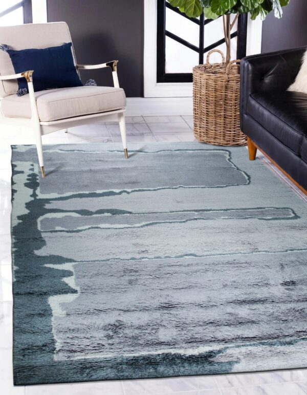 Abstract high-pile rug in gray and teal colors styled with a white armchair and black leather sofa.