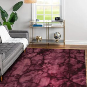 Abstract burgundy and dark purple rug grounding a gray sofa and brass console table on wood flooring.