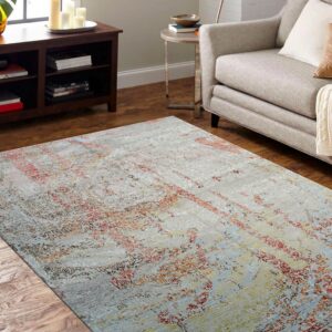 Faded gray low-pile rug with colorful distressed red and blue abstract patterns anchors a neutral living room.
