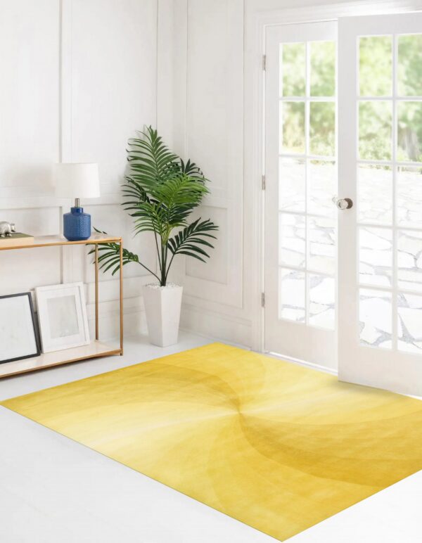 A rectangular yellow rug with a subtle radial gradient pattern rests on white flooring in a bright room.