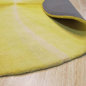 Round yellow low pile rug with a radial stripe pattern curled up on light wood flooring, revealing a gray back.