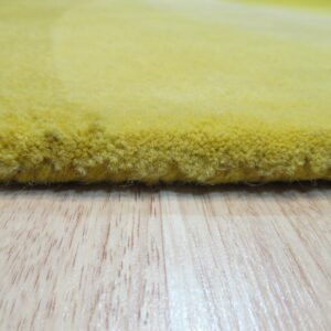 The dense, high pile edge of a yellow rug rests on light wood grain flooring.