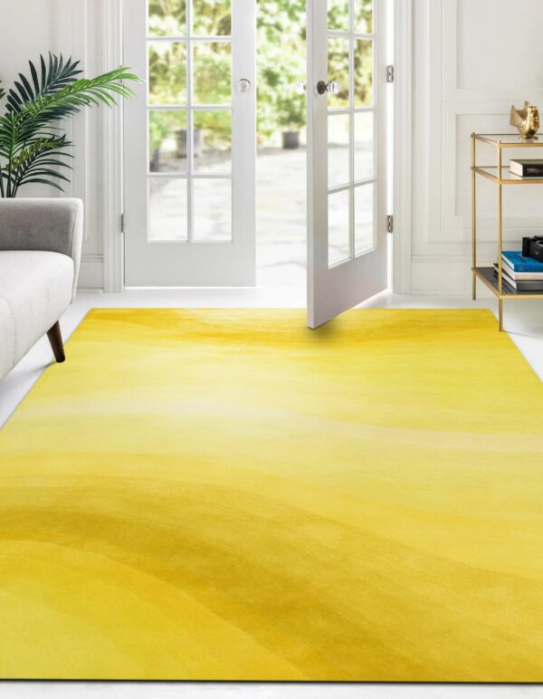 Bright yellow abstract rug sits on white floor near a gray couch and open patio doors.