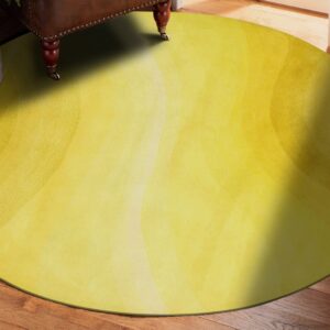 Chartreuse yellow round rug with subtle blended concentric patterns sits on dark wood planks.