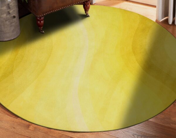Chartreuse yellow round rug with subtle blended concentric patterns sits on dark wood planks.