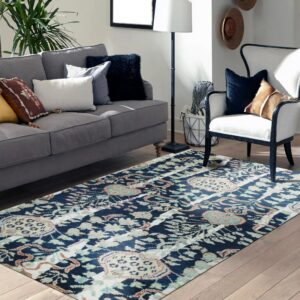 Blue, cream, and rust abstract pattern rug in a living room with a gray sofa and light wood floor.