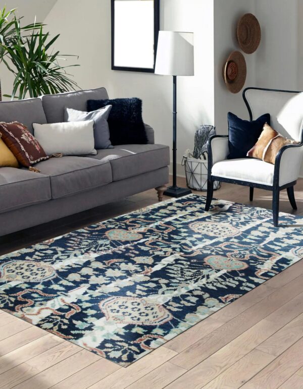 Blue, cream, and rust abstract pattern rug in a living room with a gray sofa and light wood floor.