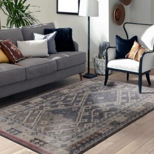 Distressed navy and tan geometric rug anchors a living room with light wood floors and grey seating.
