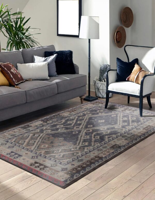 Distressed navy and tan geometric rug anchors a living room with light wood floors and grey seating.
