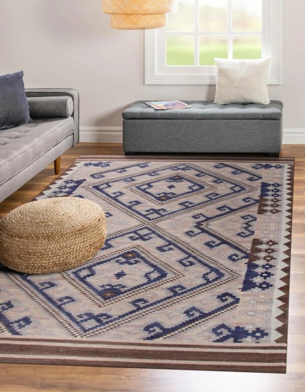 Blue, beige, and brown geometric rug anchors a living room with wood floors and gray upholstered furniture.