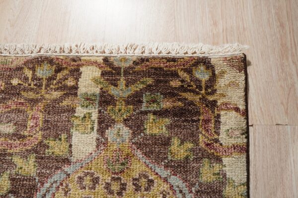 Close-up of a high-pile, brown, cream, and multicolor patterned rug with fringe on light wood flooring.