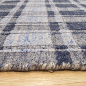 Textured blue and gray plaid rug with a visible rolled edge resting on light wood flooring.