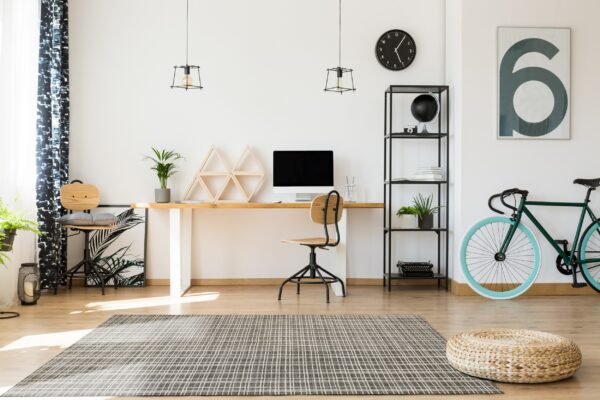 A dark gray grid rug anchors a bright modern home office with wood floors and a desk.