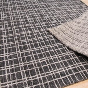 Textured gray rug with a white grid pattern, folded to show the lighter gray woven backing on wood.