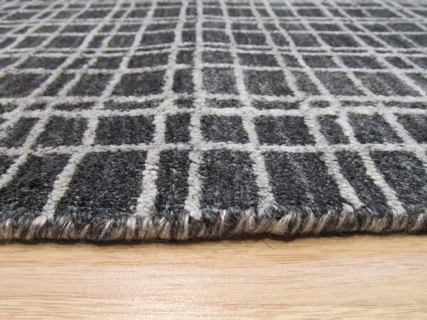 Textured gray rug with a light gray grid pattern shown closely on a light brown wooden surface.