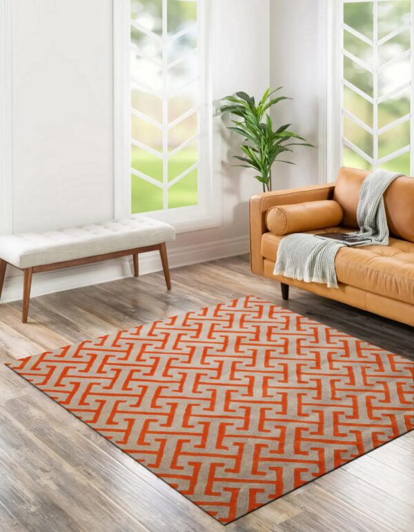 Gray and orange geometric rug in a bright room with a tan leather couch and wood plank floor.
