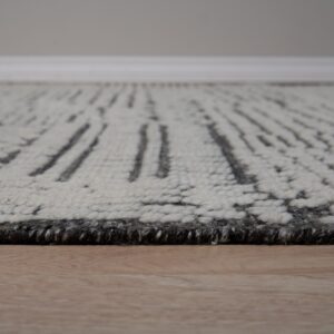 Textured high-pile cream rug with a dark gray abstract dashed pattern rests on wood flooring.