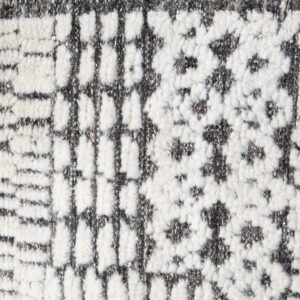 Close-up view of a high-pile rug featuring an abstract geometric pattern in cream and speckled gray.