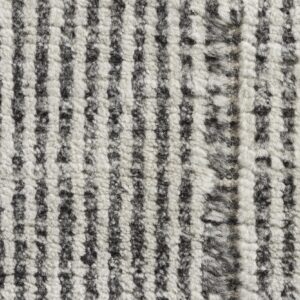 Detail view of a textured, high-pile rug showing irregular vertical stripes in black and fluffy white.