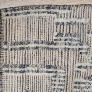 Cream and dark gray textured rug featuring vertical stripes and abstract geometric patterns on light wood flooring.