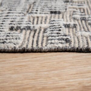 The high-texture gray and cream geometric patterned rug rests on light blonde hardwood flooring.