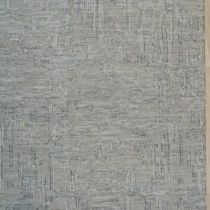 Textured gray rug displaying a dense linear geometric pattern, placed on light wood plank flooring.