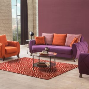 A red and cream geometric rug anchors a purple sofa and orange armchairs on a light wood floor.