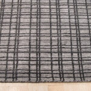 Textured light gray rug featuring a dark grid pattern placed on light colored wood flooring.