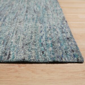 Thick pile rug in shades of blue, teal, and gray resting on light hardwood floors.
