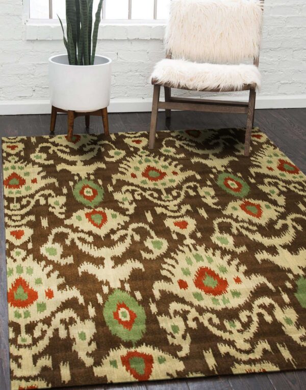 A brown, beige, green, and rust ikat patterned rug rests on dark wood flooring beside a furry white chair and a potted snake plant.