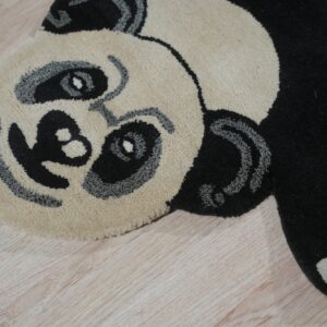 Close-up of a cream, black, and gray high-pile panda rug on light wood floors.