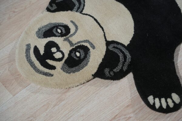 Close-up of a cream, black, and gray high-pile panda rug on light wood floors.