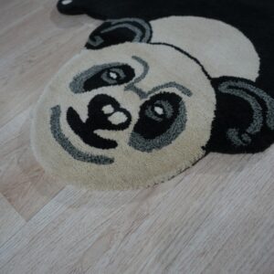 A black, cream, and gray panda-shaped rug rests on light wood plank flooring.