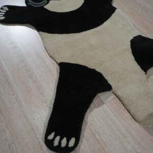 Black and cream panda-shaped rug featuring glasses, lying flat on light wood plank flooring.