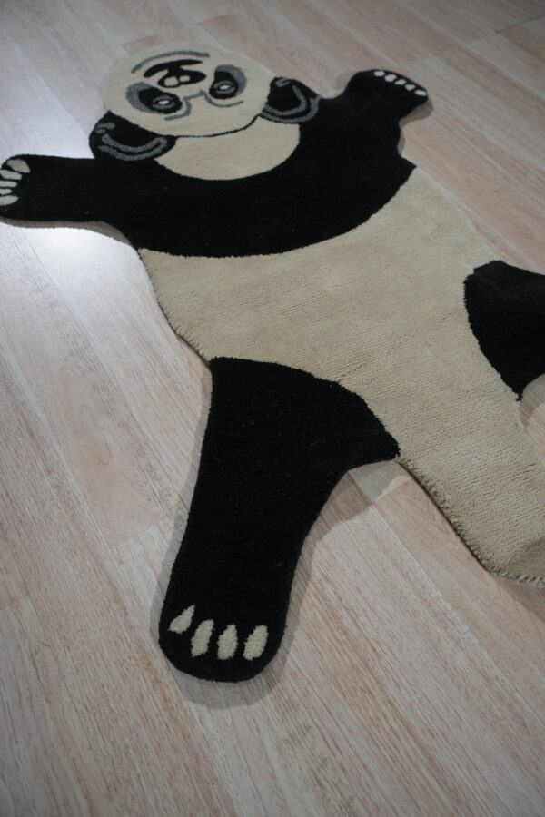 Black and cream panda-shaped rug featuring glasses, lying flat on light wood plank flooring.
