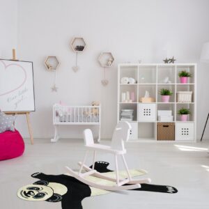 Black and cream panda rug on a light wood floor in a nursery with white crib and shelving.