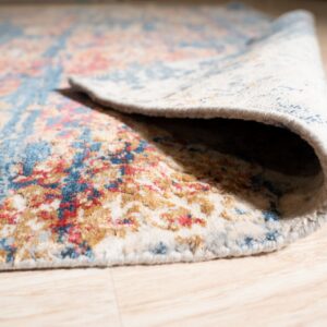 A distressed blue, red, and gold patterned rug is rolled back on a light wood plank floor.