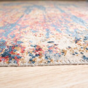 Abstract patterned, low-pile rug in cream, blue, and coral colors on light wood flooring.