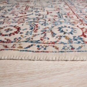 Medium pile cream rug with red and blue traditional motifs resting on light wood grain floor.
