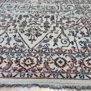 Traditional cream rug with a distressed blue and burgundy pattern on light wood floor.
