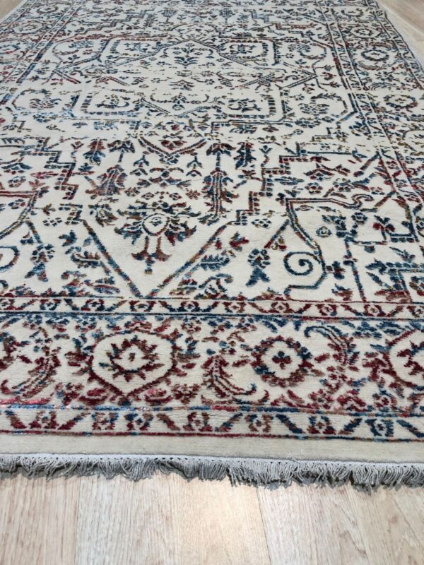 Traditional cream rug with a distressed blue and burgundy pattern on light wood floor.