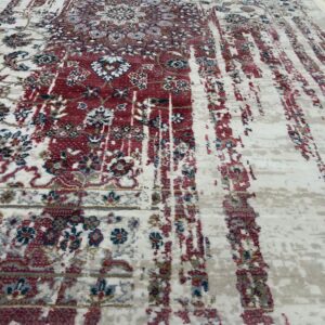 Cream rug with heavily distressed red, blue, and gray traditional patterns lying on light wood floors.