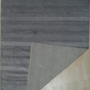 Textured gray rug featuring horizontal stripes and patterned bands, revealing a plain backing on light flooring.
