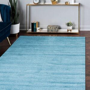 Blue and white striated rug on dark wood floors next to a velvet chair and gold console table.